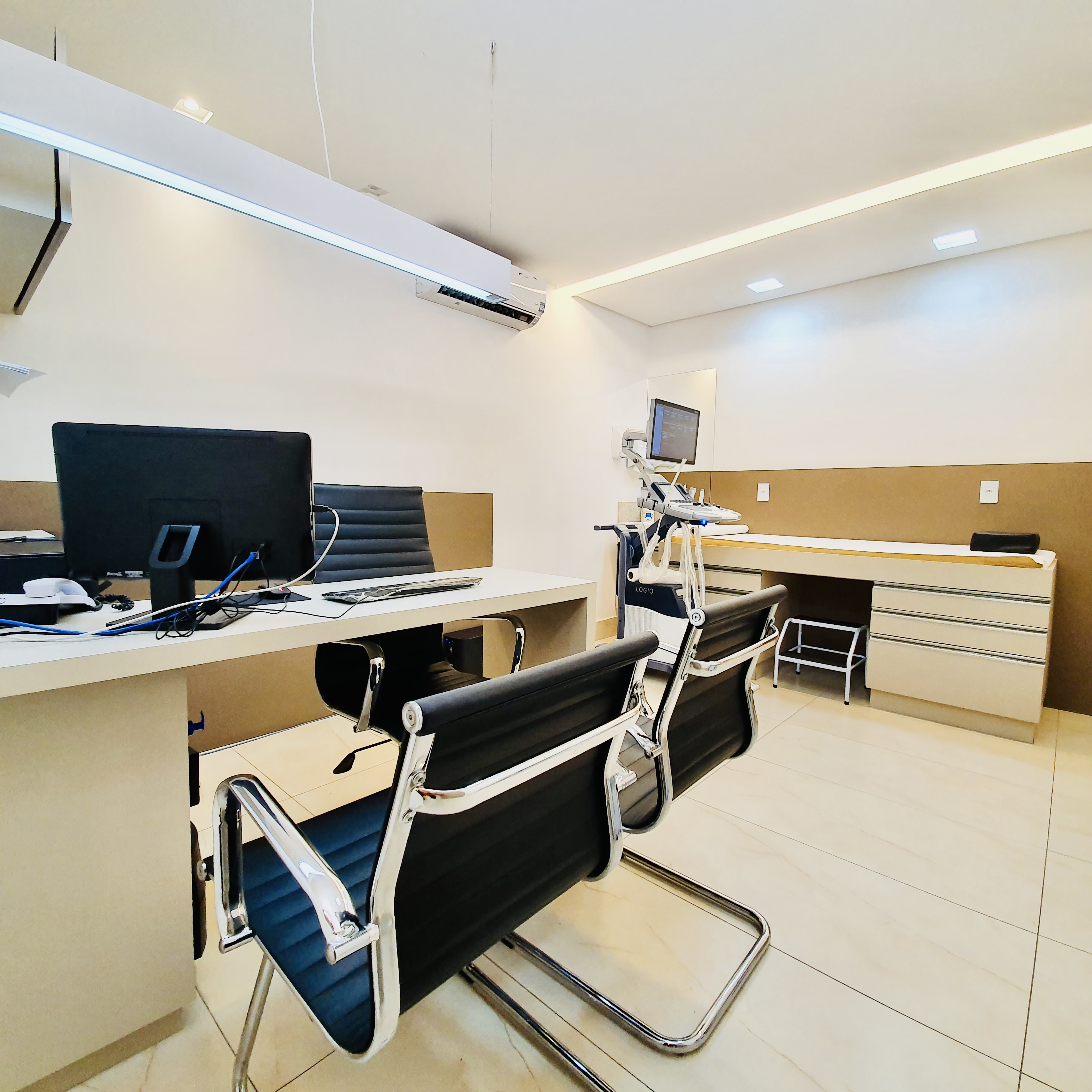 Consultório de ultrassonografia do Instituto Valler com mesa, cadeiras e equipamento.